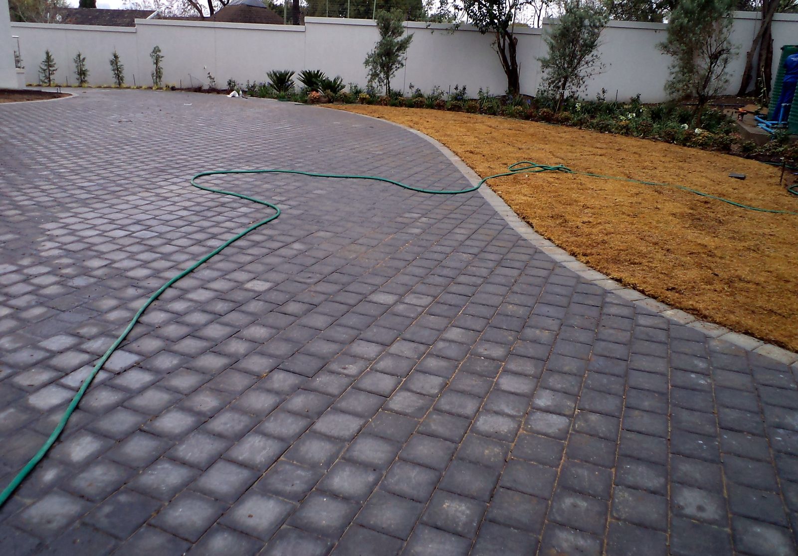 Charcoal paved residential driveway curving past a garden bed